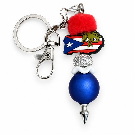 Puerto Rico Coquí frog keychain with red pom pom and blue bead on white background